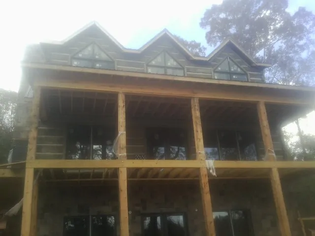 Dormers and porch framing on a large log home under construction — Roof Coating work by our crew in Falmouth