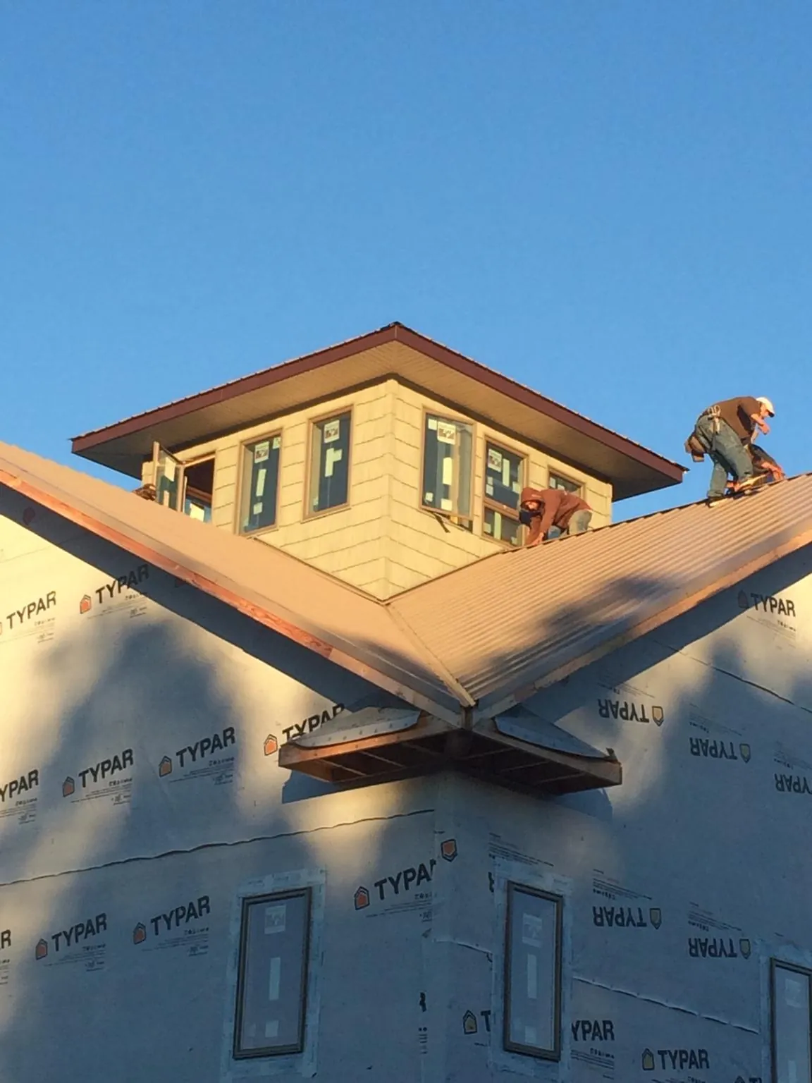Roofers working around a rooftop cupola on a new metal roof at sunset — Roof Waterproofing in Falmouth by Roofing Brothers